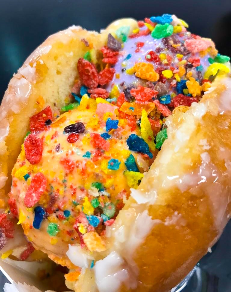 a donut filled with ice cream scoops and topped with fruit pepples