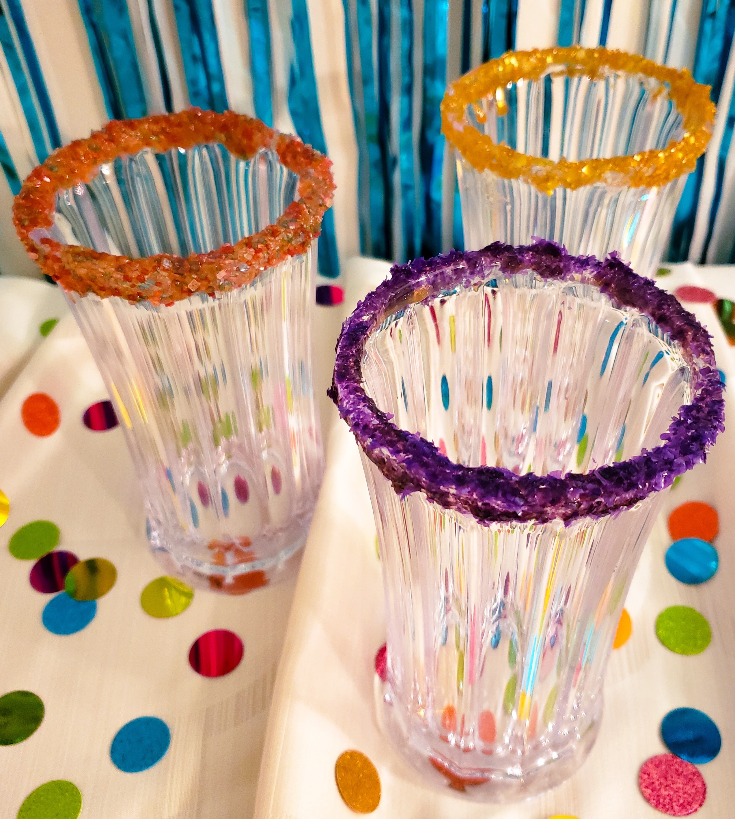 three fancy glasses with purple, orange and yellow sugar rims