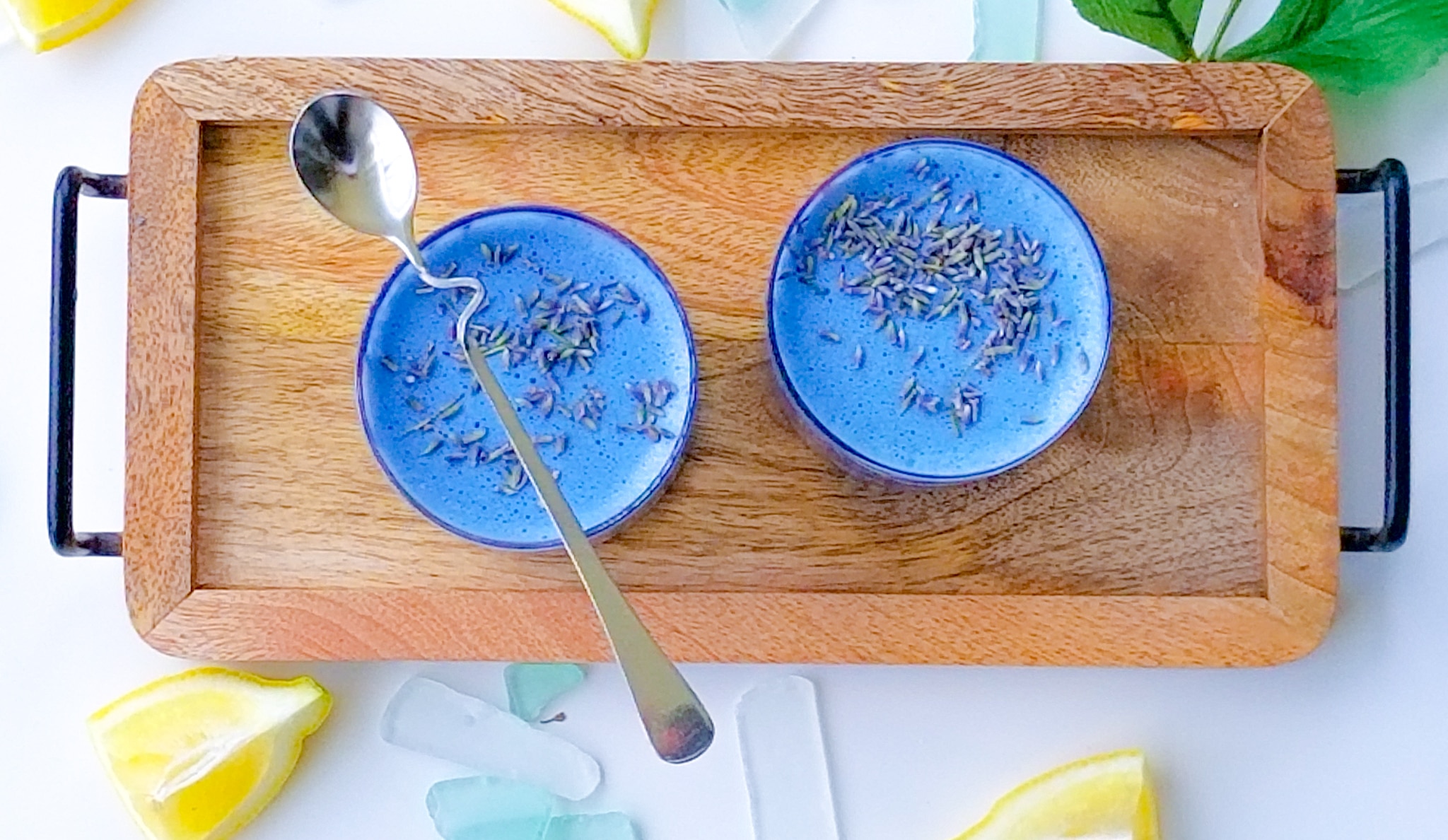 two glasses of blue milk on a wooden serving board