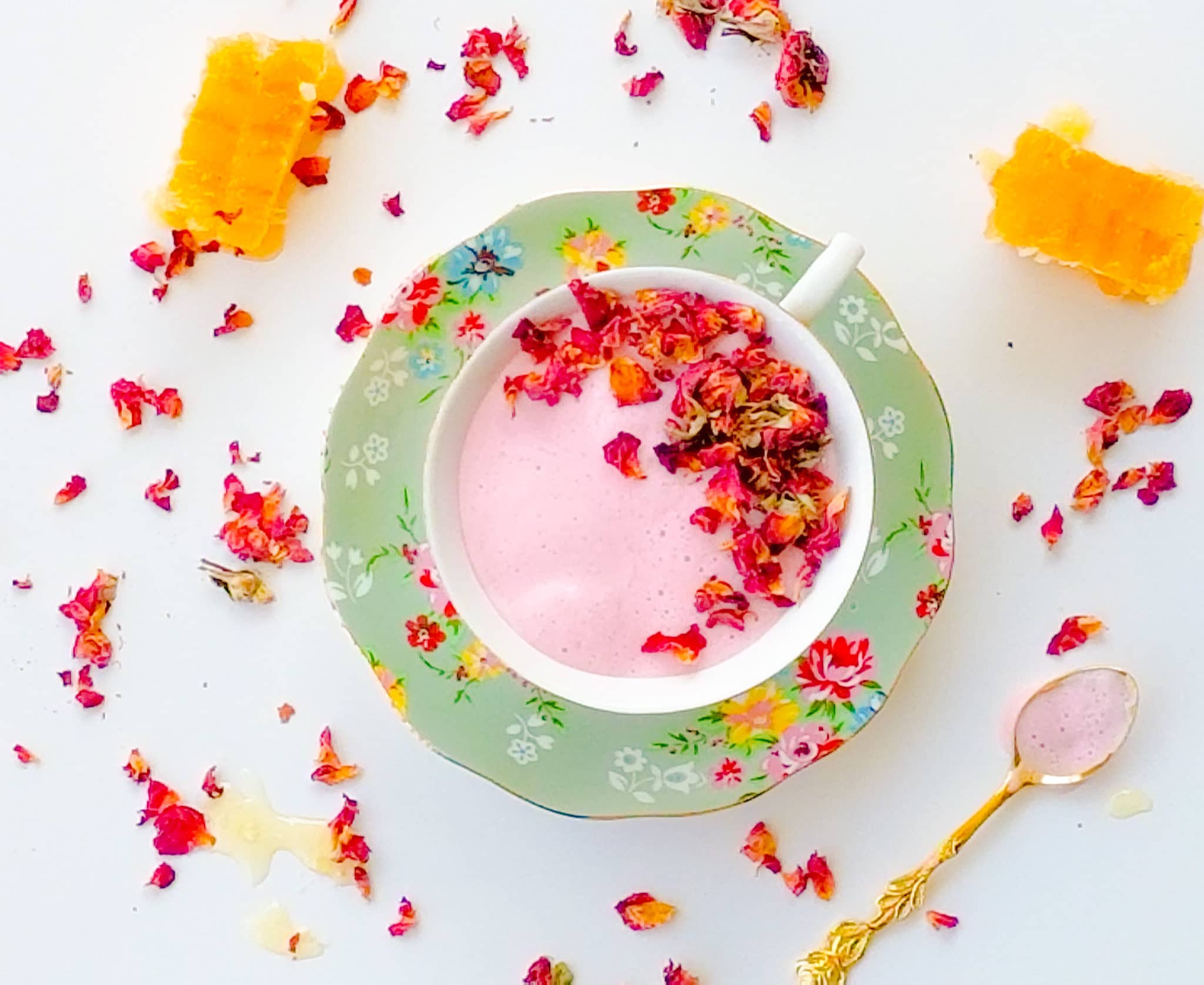 a teacup of pink milk on a floral saucer
