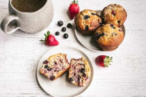 Berry Muffins on white serving plates with a side of coffee