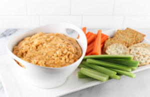Buffalo Chicken Dip in a dish with veggies and crackers on the side