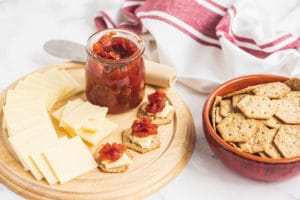 Cheddar and Tomato-Jam Canapés with the ingredients spread around on wooden serving boards