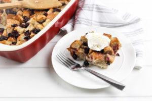 Cherry Bread Pudding in a red baking dish with a side served with ice cream
