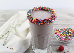 Chocolate Milk Chiller in a glass with the rim garnished with chocolate and sprinkles