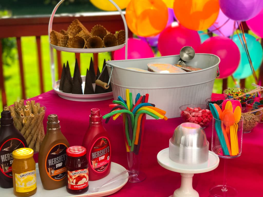 a party table with all the fixings for an ice cream sundae bar