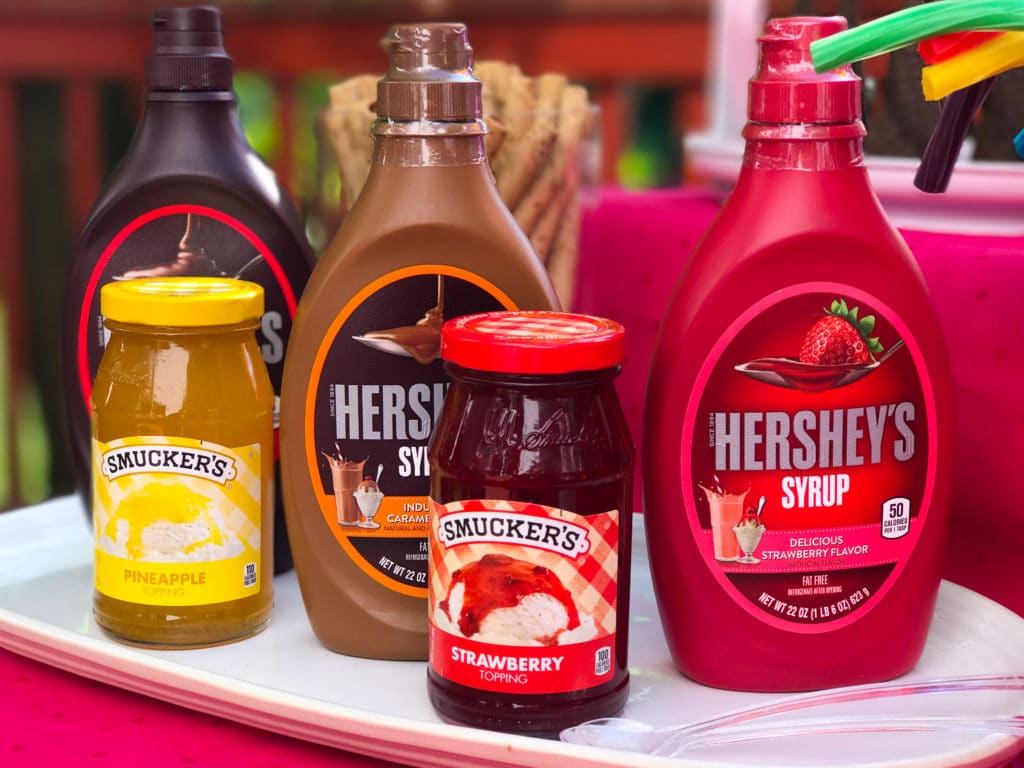 3 bottles of different flavored hershey's syrup and two jars of smuckers ice cream topping