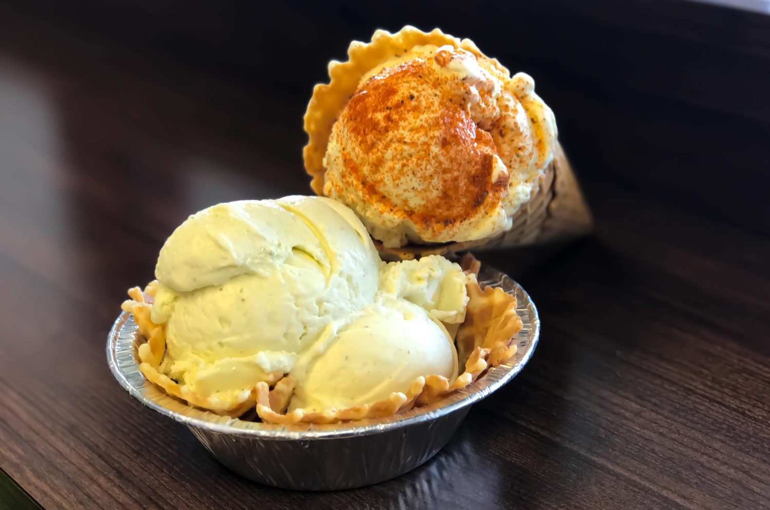 a nice cream cone topped with cinnamon and a waffle cone bowl of vanilla ice cream
