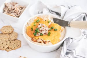 Hot Crab Dip in a bowl garnished with cheese and green onions
