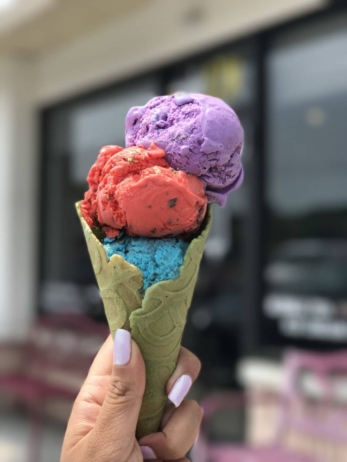 a waffle cone topped with blue, red and purple ice cream scoops