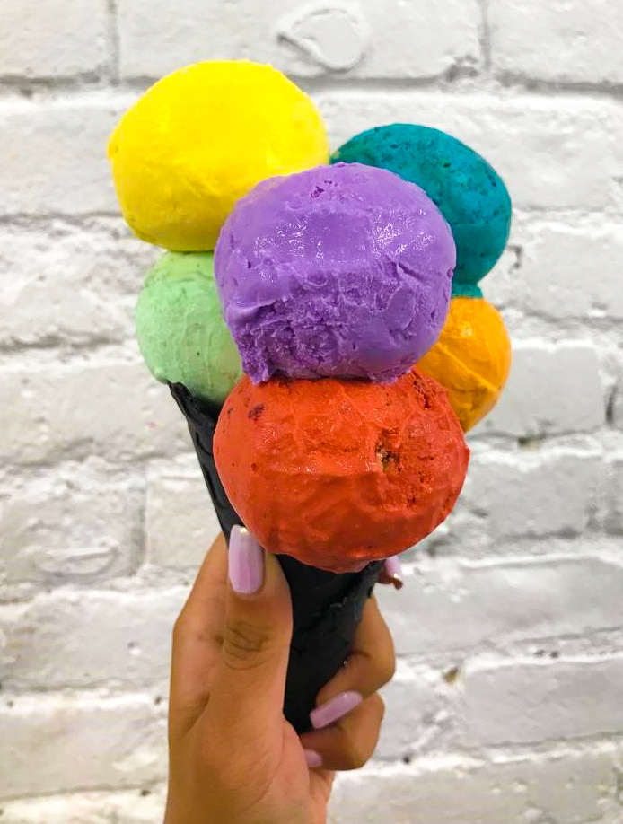 an ice cream cone with 6 scoops of vibrant colored ice cream on top
