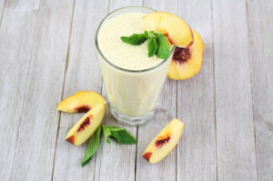 Peaches and Cream Smoothie in a glass garnished with peach slices and mint leaves