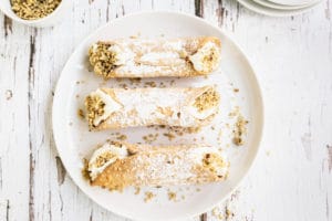 Classic Cannolis - three on a white plate garnished with nuts