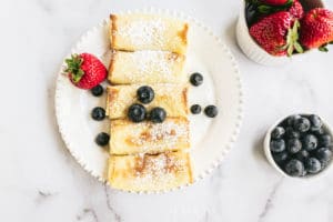 Cheese Blintzes on a plate with blueberries and strawberries