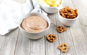 Chocolate Salted Caramel Dip in a white dish with pretzels on the side