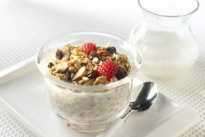 Homemade Low-fat Granola in a dish on top of yogurt with berries.