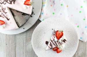 Strawberry Drizzle Ice Cream Cake garnished with chocolate syrup and strawberry slices