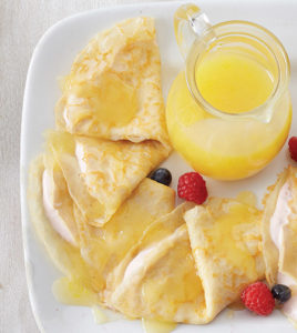 Lemon Berry Crepes on a plate with a side of berries and lemons