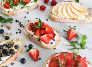 Slice of bread topped with ricotta cheese, delicious sliced strawberries, and a drizzle of honey.