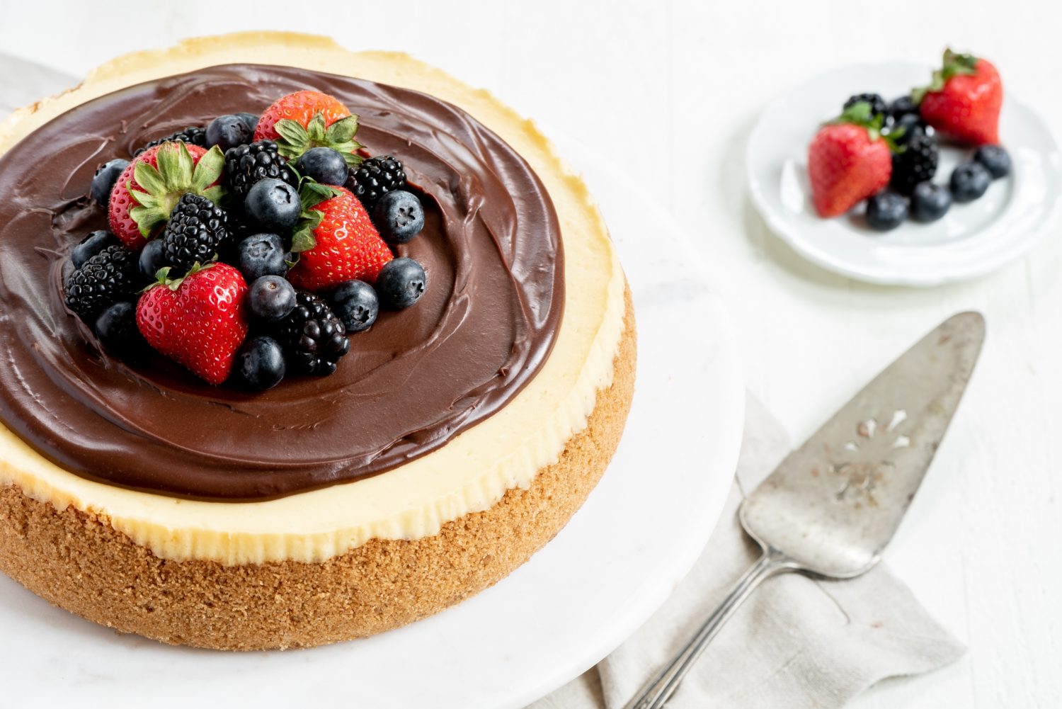 cheesecake with chocolate frosting on top and assorted berries as garnish
