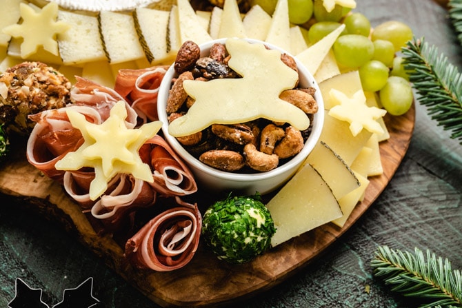 holiday cheese board with a reindeer and snowflakes cut out of cheese