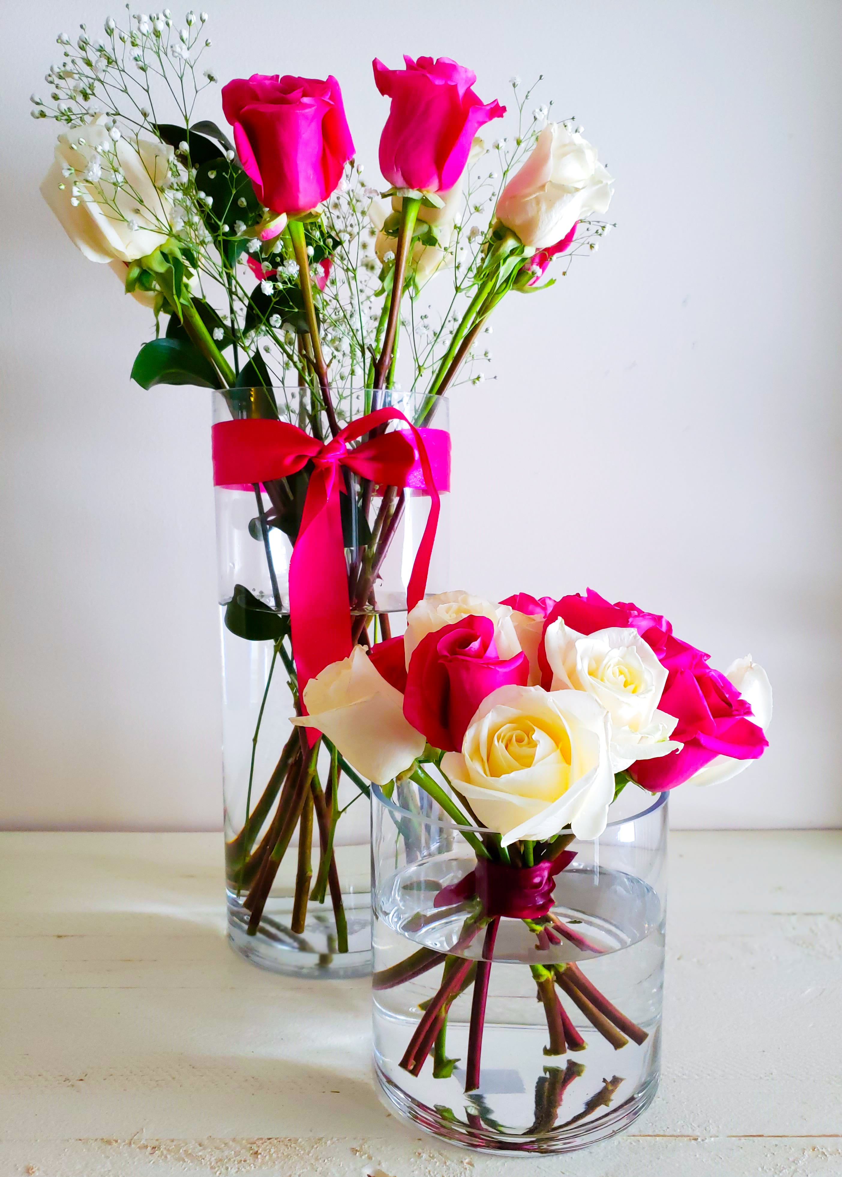 a vase of long stem roses that are white and pink