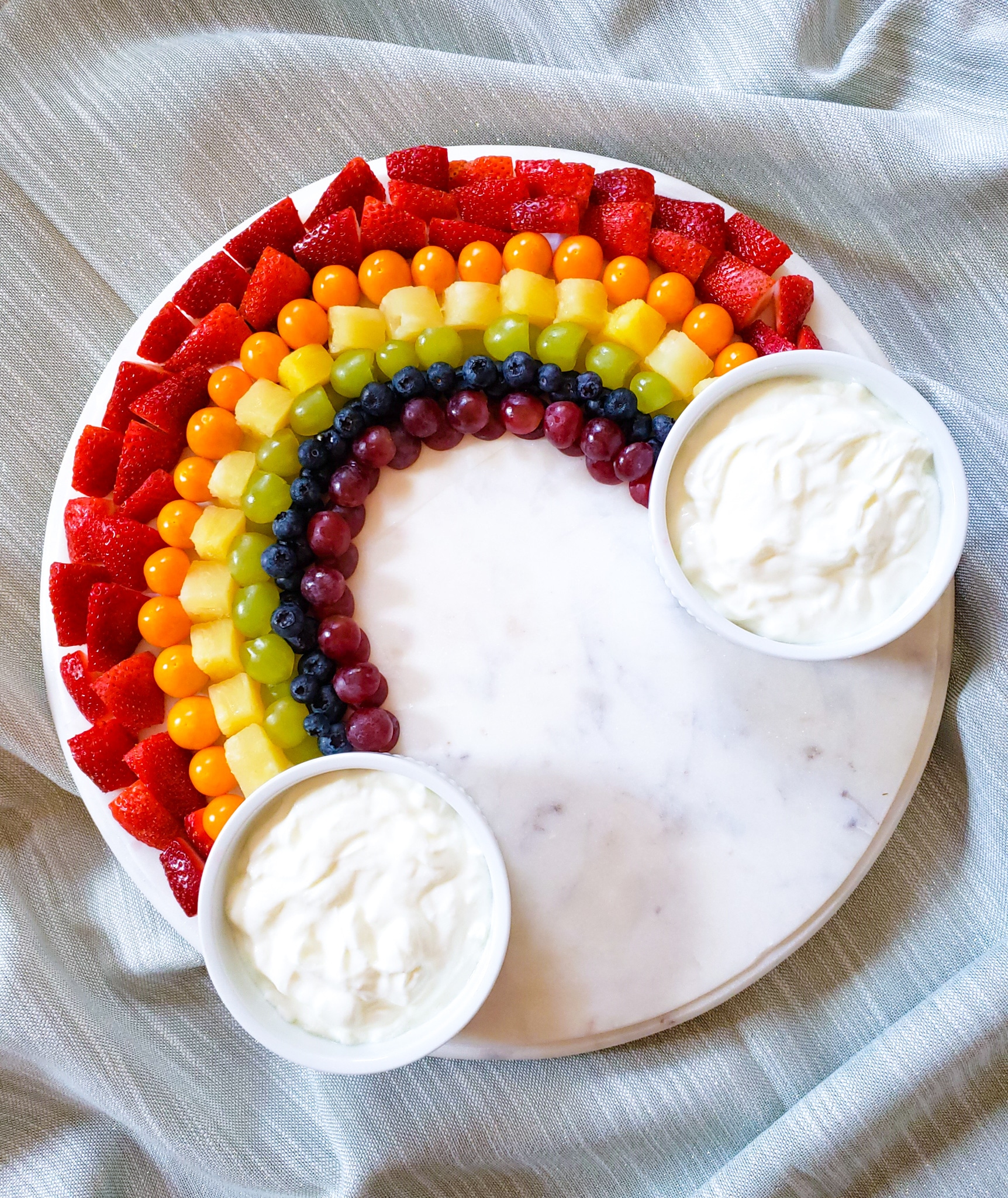 a rainbow of different colored fruits with dips at the ends