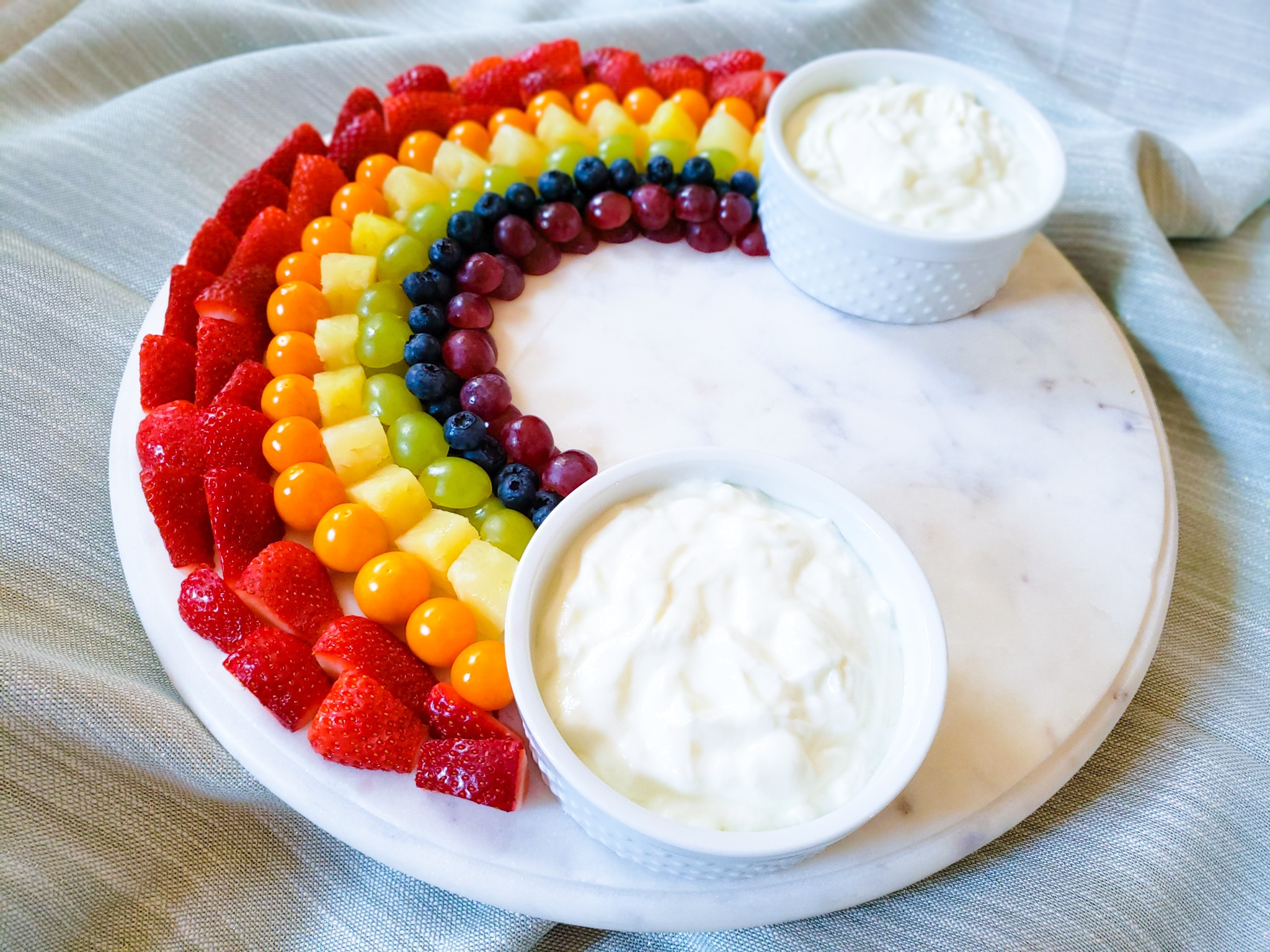 a rainbow of fruit with dips at the end