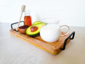 milk, avocado and honey on a wooden serving tray