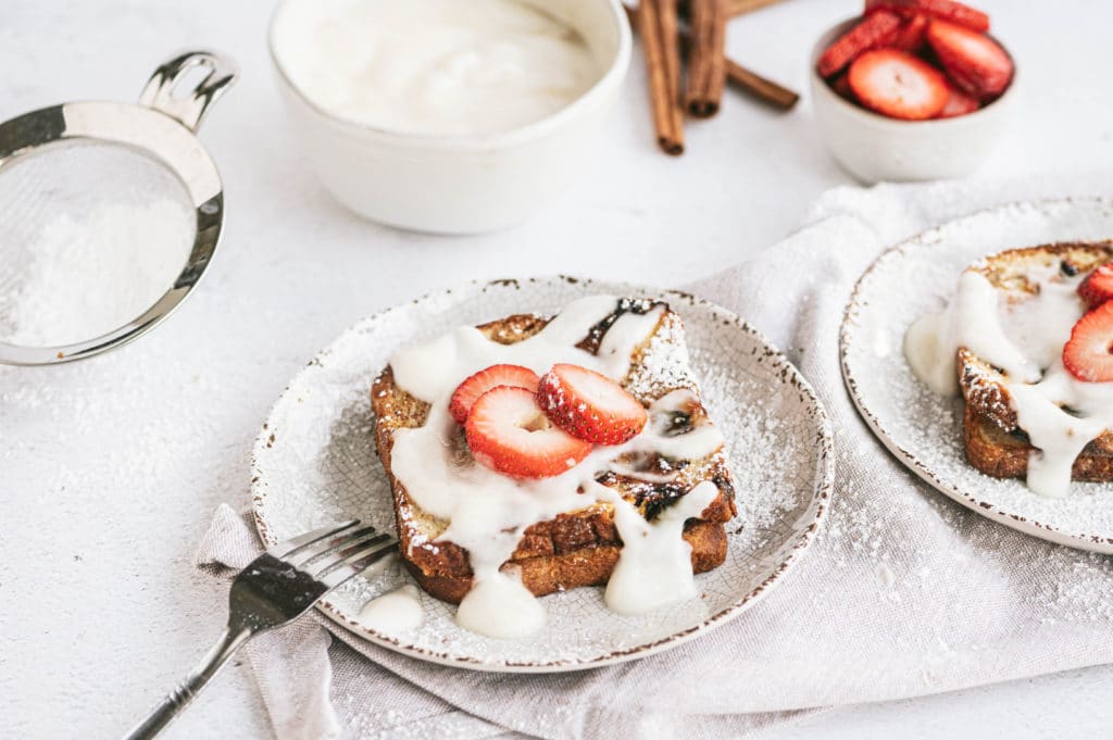 french toast topped with yogurt sauce, powdered sugar and strawberry slices
