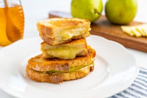 One pear and honey grilled cheese sandwich, with the other one cut in half.