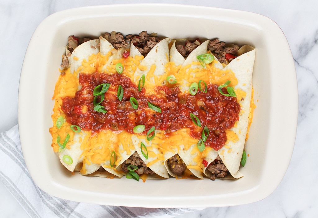 Five savory beef enchiladas, baked to perfection with melted cheese, and topped with salsa and chopped green onions.