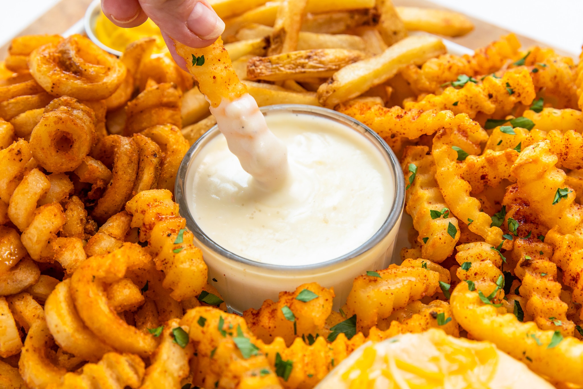A finger dipping a fry in mayo, adding a tangy twist to the classic snack.