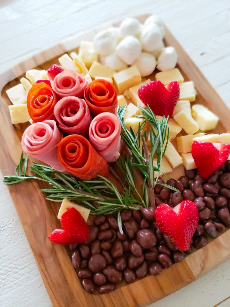 a beautiful charcuterie board with the meats rolled to look like flowers