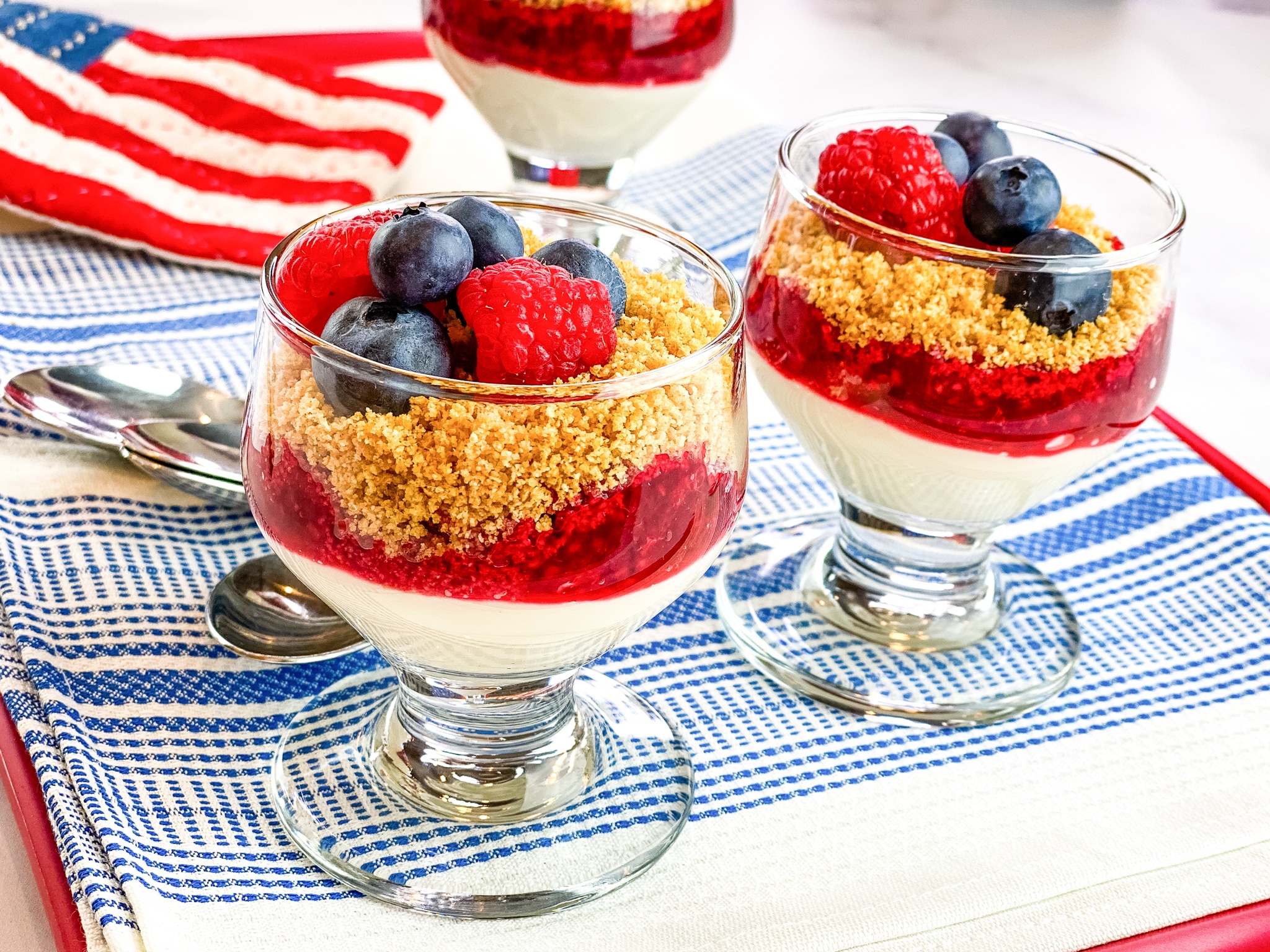 mini cheesecakes are in small glass serving bowls topped with granola and berries