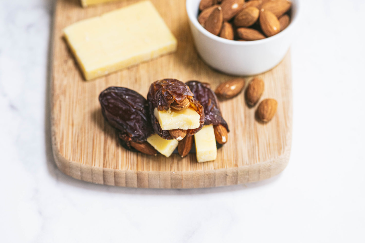 dates with tiny slices of cheese stuffed inside on a wooden cheese board