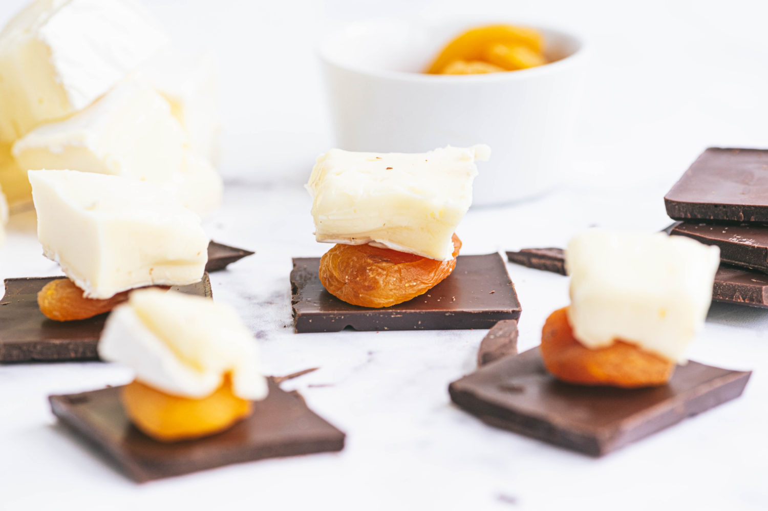 pieces of very dark chocolate topped with dried apricots and cheese