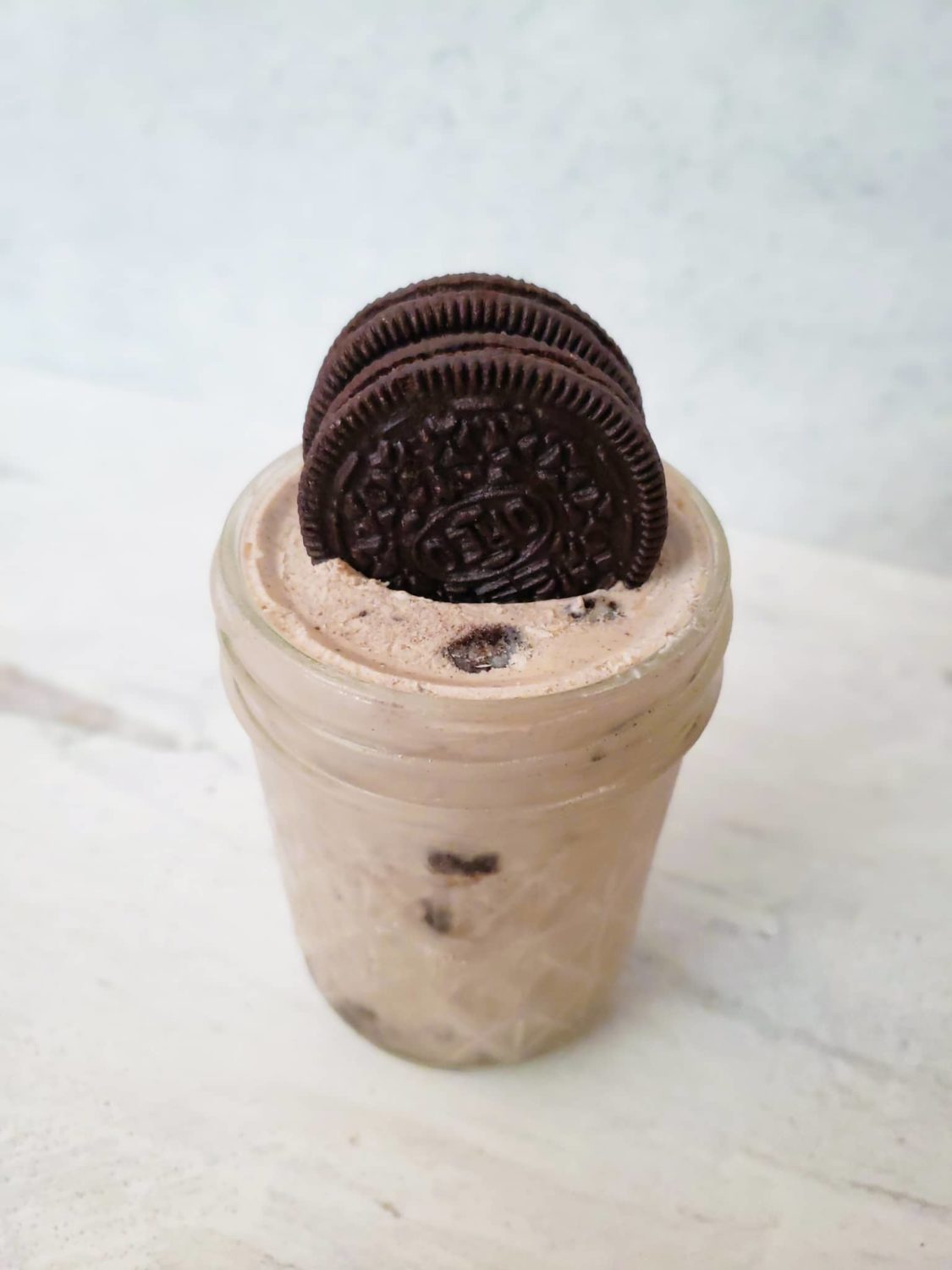 cookies and cream ice cream in a small mason jar topped with two oreos