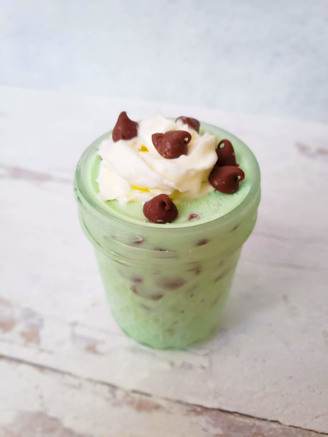 mint chocolate chip ice cream in a small mason jar with whipped cream and chocolate chips on top