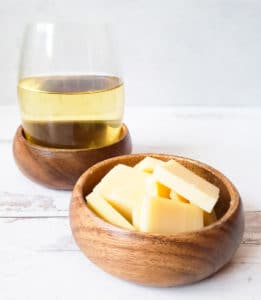 glass of white wine with a bowl of cheese slices