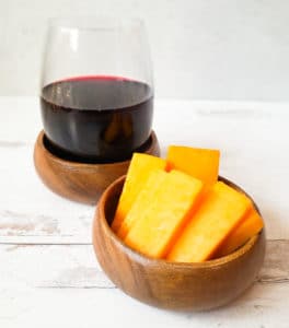 red wine with a bowl of orange cheese slices