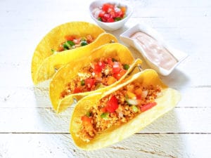 three Masala Paneer Street Tacos with a side of yogurt sauce and tomatoes