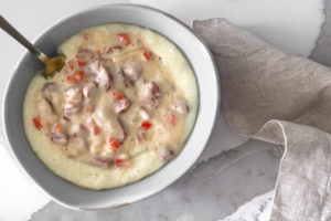 a bowl of Andouille Gravy over Smoked Gouda Grits with a spoon ready to dig in