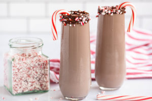 Chocolate Candy Cane Milk in two glasses with chocolate rimmed glasses and candy canes