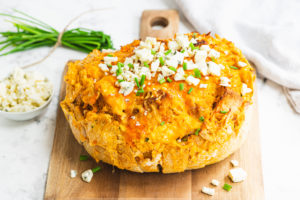 a loaf of bread topped with buffalo chicken and blue cheese
