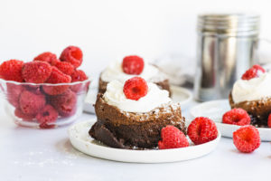 chocolate lava cakes topped with whipped cream and raspberries