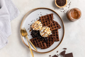a photo of chocolate waffles garnished with caramel and chocolate shavings