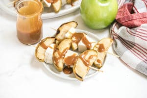 apples on a skewer with caramel drizzled over it