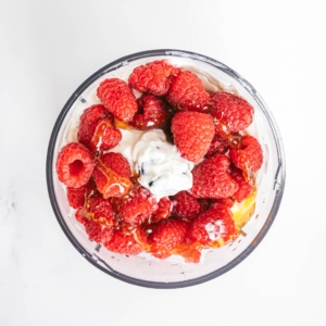 bowl of yogurt topped with raspberries and honey