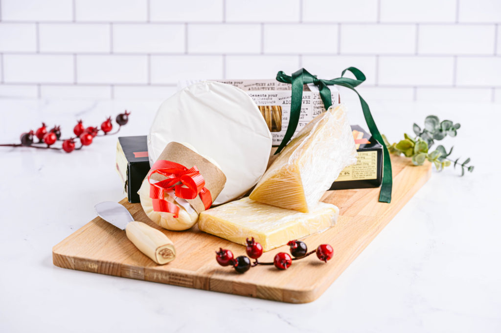 Charcuterie board set with cheese knife and variety of cheeses decorated with cranberries.